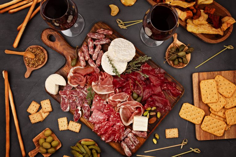 Appetizers table with differents antipasti, charcuterie, snacks and wine. Sausage, ham, tapas, olives, cheese and crackers for buffet party. Top view, flat lay