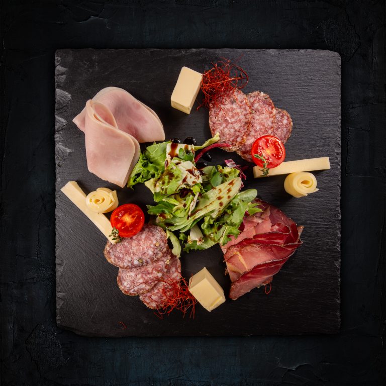 Cold meat board with prosciutto, slices ham, salami and fresh lettuce